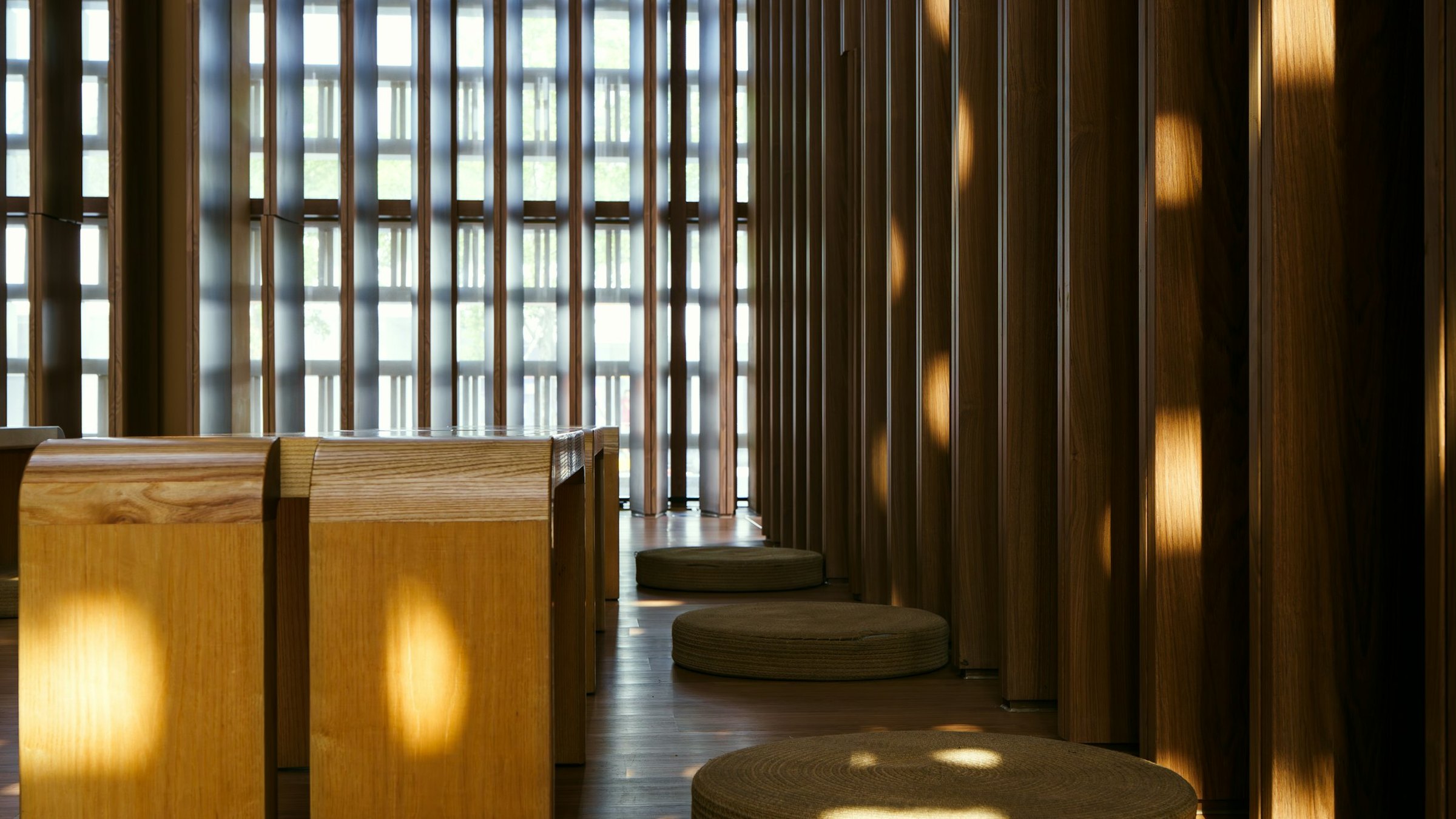 Naturally lit timber interior with quiet seating and a view into greenery